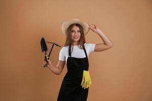Labor conception. Gardener is, with ,tools. Young pretty woman is against background in the studio photo