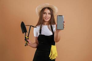 Modern, technology, smartphone with copy space, gardener. Young pretty woman is against background in the studio photo