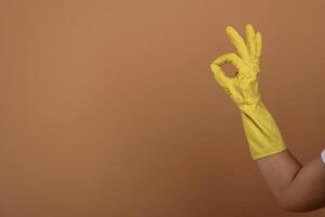 Close up view of woman hand in yellow glove that is showing okay or fine gesture photo