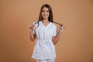 Standing, with stethoscope. Young pretty woman is against background in the studio photo