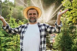 Automatic watering,, system behind. Senior gardener is at work at daytime photo