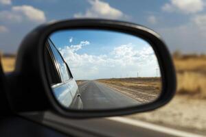 Close up of car rear view mirror with reflection of empty highway. Concept of of travel photo