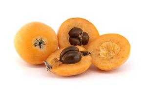 A close-up of fresh loquats, with some cut open to reveal their seeds and soft texture. photo