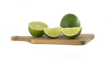 Fresh limes and slices resting on cutting board photo