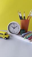A workspace scene featuring a calculator, clock, colorful pens, and stationery items. A hand is reaching for the calculator, with yellow background adding vibrancy Colorful Workspace Clock, Stationery video