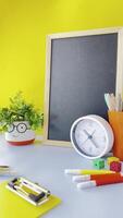colorful workspace featuring globe, clock, stationery items on bright yellow background scene includes chalkboard, pens, dice, creating educational atmosphere. Bright Cheerful Workspace Stationery video