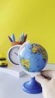 Colorful Globe on Desk with Stationery and Clock. Vibrant Workspace with Writing Tools and Clock A clock, a cup of pens, and a toy car are visible on desk, creating vibrant study, workspace atmosphere video