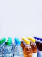 Plastic water and beverage bottles with multicolored caps arranged in rows for packaging and consumer product display. Selective focus 03 photo