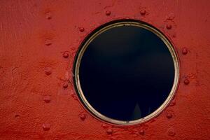 A detailed closeup of a round porthole with a protective glass on the brown painted old boat wall. Brooms are stored inside 09 photo