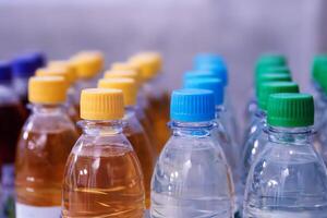 Plastic water and beverage bottles with multicolored caps arranged in rows for packaging and consumer product display. Selective focus 01 photo