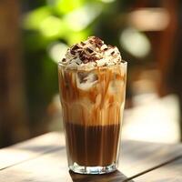 Refreshing Iced Coffee Drink with Cream and Chocolate Shavings in a Clear Glass on a Wooden Table Surrounded by Lush Greenery photo
