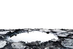 Reflective Water Pool on Rough Terrain Surrounded by Cracked Earth and Pebbles Under Bright White Sky, Capturing Nature's Unique Elements and Texture photo