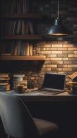 A laptop sits on a desk in front of a brick wall photo