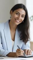 A woman in a business suit is smiling while writing on a piece of paper photo