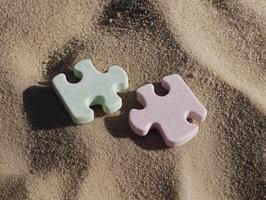 Two pieces of puzzle pieces on the brawn sand photo