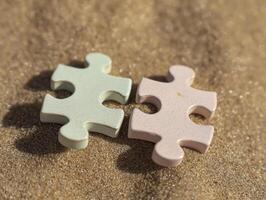 Two pieces of puzzle piece on the sand photo
