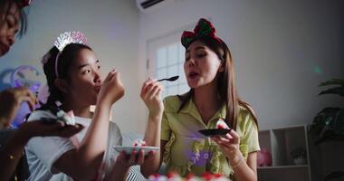 Handheld zoom in shot, Three friends are enjoying a cake on a sofa in a warmly decorated room at home. Share special moments together at home video