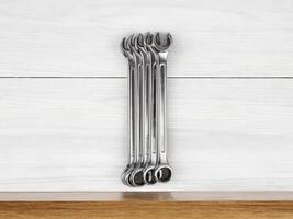 A meticulously arranged set of spanners on white wooden surface, radiating sense of neatness and preparedness photo