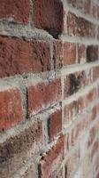 A red brick wall with rough texture and visible mortar joints, showcasing rustic and industrial aesthetic photo