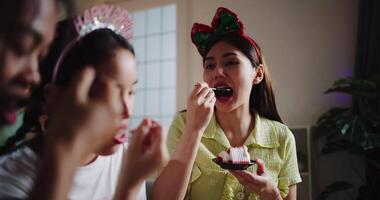 Handheld selective focus shot, Three friends are enjoying a cake on a sofa in a warmly decorated room at home. Share special moments together at home video