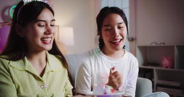 Handheld zoom in shot, Two friends are enjoying a cake on a sofa in a warmly decorated room at home. Share special moments together at home video