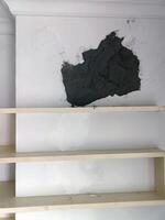 A patched wall is an eyesore, as dark gray patch stands out against white paint, showing neglected spot begging for paint to blend it seamlessly photo