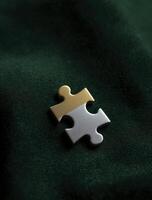 Single gold puzzle piece sparkles with sense of hope and completion, suggesting solutions and path forward on dark green background photo