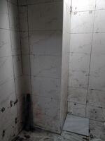 Bathroom corner with white tile and drain shows worn, unkempt state of being as grout is dirty and floor is stained, creating feeling of neglect photo