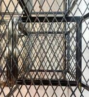 Geometric pattern of intersecting metal grids creates complex, industrial design. black metal framework contrasts with light background, forming striking visual effect photo