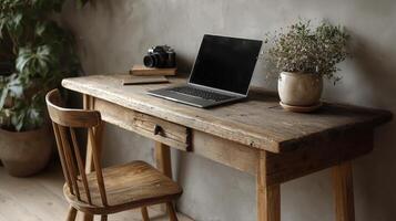 Rustic wooden desk with open laptop, camera, and potted plant creates cozy workspace. natural light and greenery add calming atmosphere photo