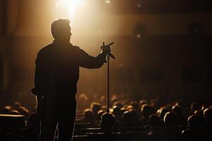 A man is standing in front of a crowd with a microphone photo