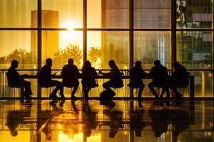 Silhouette of business people at a conference table in front of large windows photo