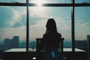 A woman sitting at a desk looking out a window photo