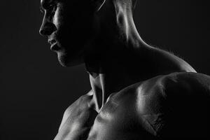 A man with a muscular body is posing in black and white photo