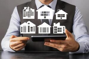 A man in a suit holding a tablet with a house icon photo