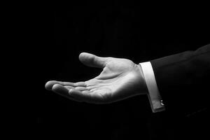 Black and white photo of a man in a suit holding out his hand