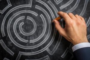 A man in a suit is drawing a maze on a blackboard photo