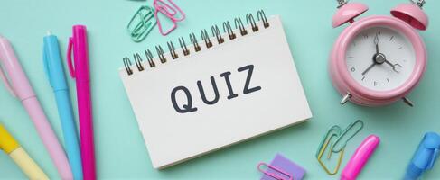 The Quiz Notebook Surrounded by Colorful Stationery and an Alarm Clock photo