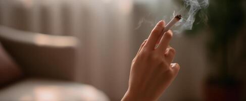 The hand holding a cigarette in a cozy indoor environment photo