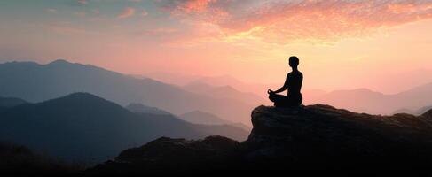 The silhouette of a meditator enjoying a serene sunset in the mountains. photo