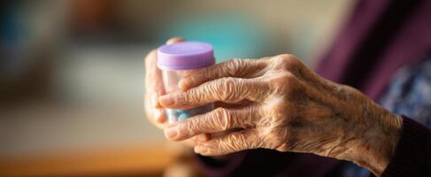 The elderly woman's hands holding a colorful medication bottle with care. photo