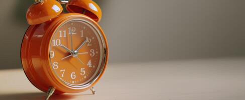 The vibrant orange alarm clock on a wooden surface radiating warmth and nostalgia. photo