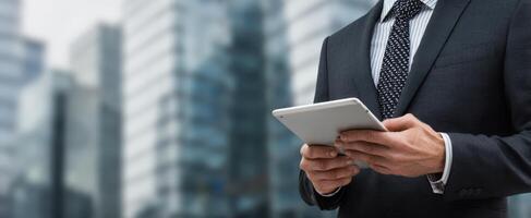 The businessman using a tablet in a modern urban environment for productivity. photo