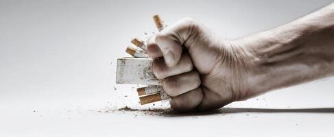 The fist crushing a pack of cigarettes symbolizes the fight against addiction. photo