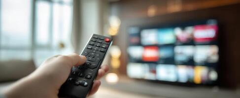 The remote control in hand pointing towards a modern living room television. photo