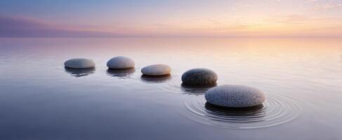 The tranquil stones creating ripples in a serene water landscape at sunset. photo