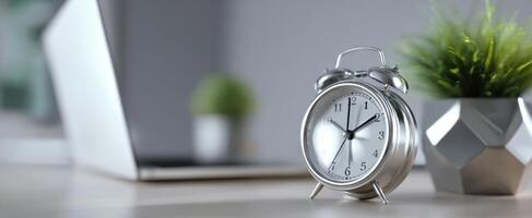 The classic alarm clock next to a modern laptop in a stylish workspace. photo