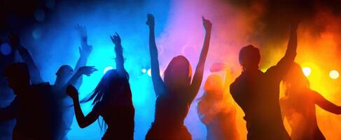 The energetic dancers silhouetted against colorful lights and smoke at a lively party. photo