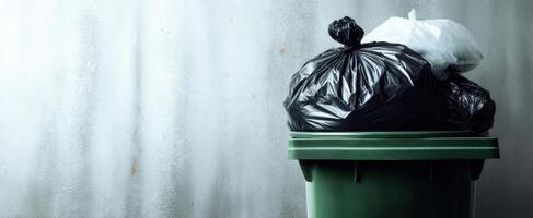 The overflowing waste bin surrounded by black garbage bags in an urban setting. photo