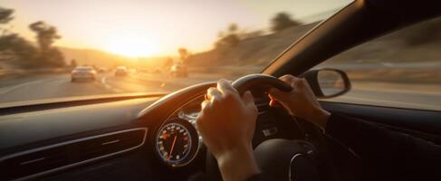 The hands gripping the steering wheel at sunset during a scenic drive. photo